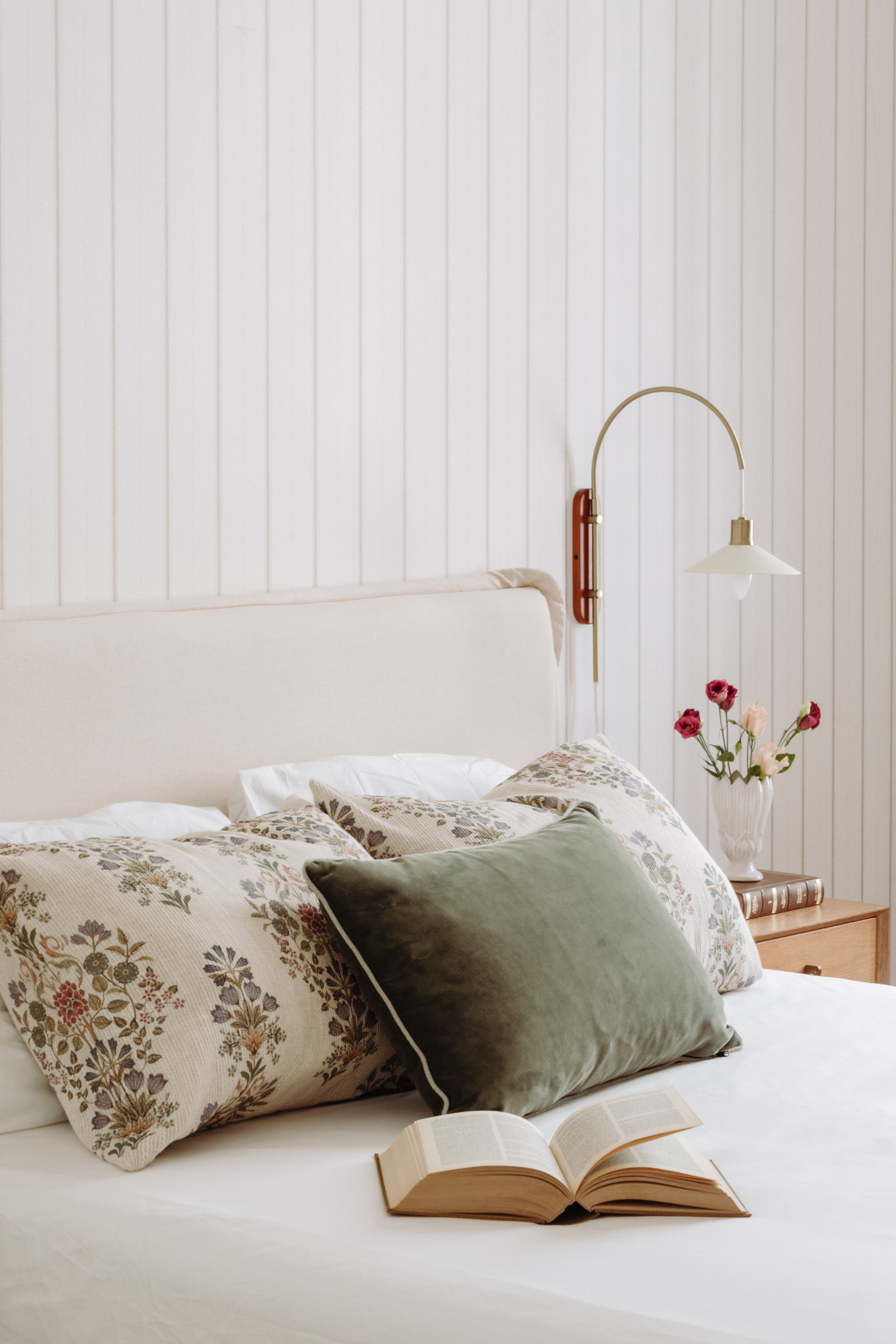 Detalle cobecero tapizado de la cama, con cojines y aplique