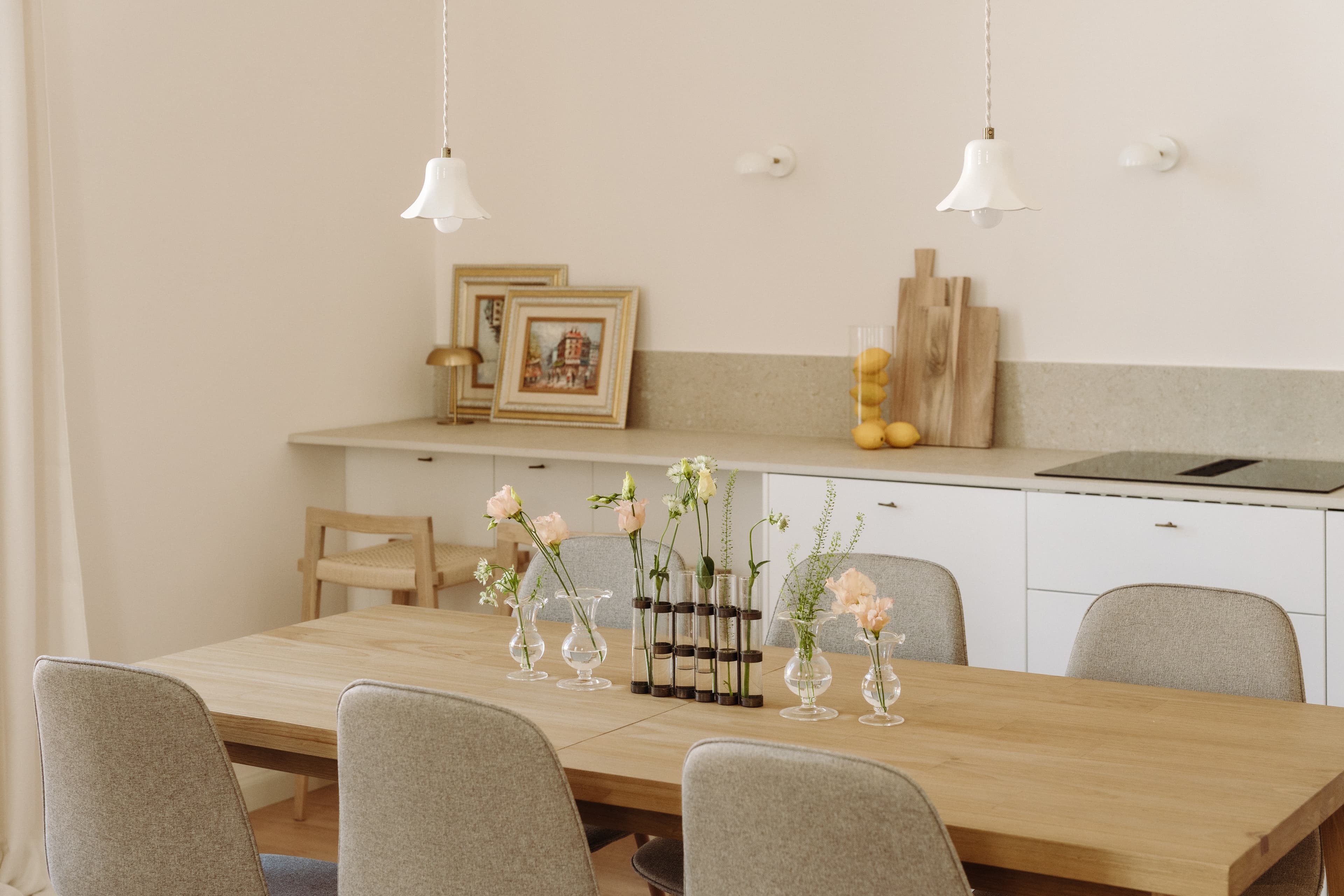 Mesa de comedor con flores, con cocina al fondo