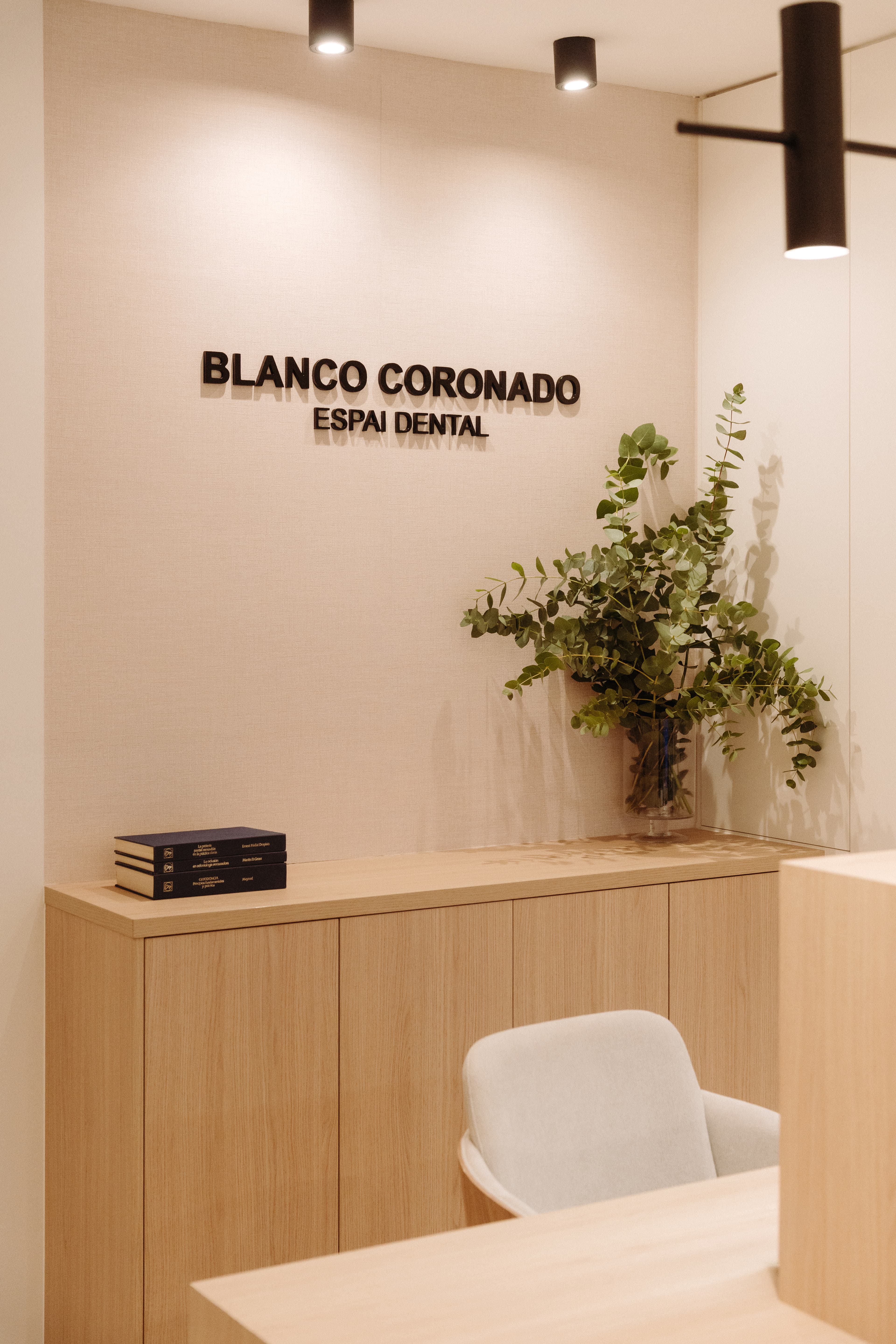 Detalle de la pared trasera del mostrador, con el nombre de la clínica con letras negras en relieve