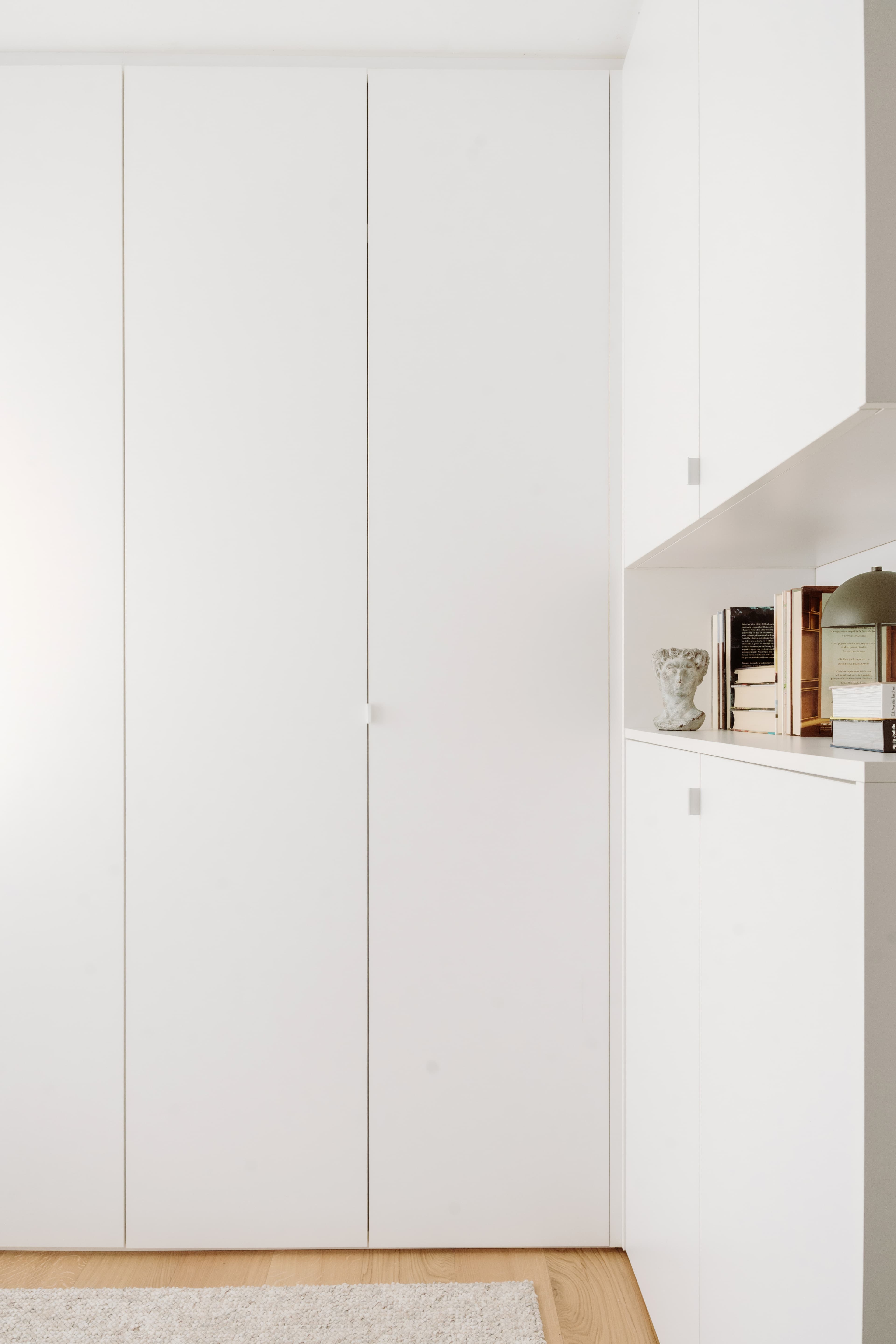 Vista de los armarios del vestidor, con la hornacina con libros y decoración a la derecha
