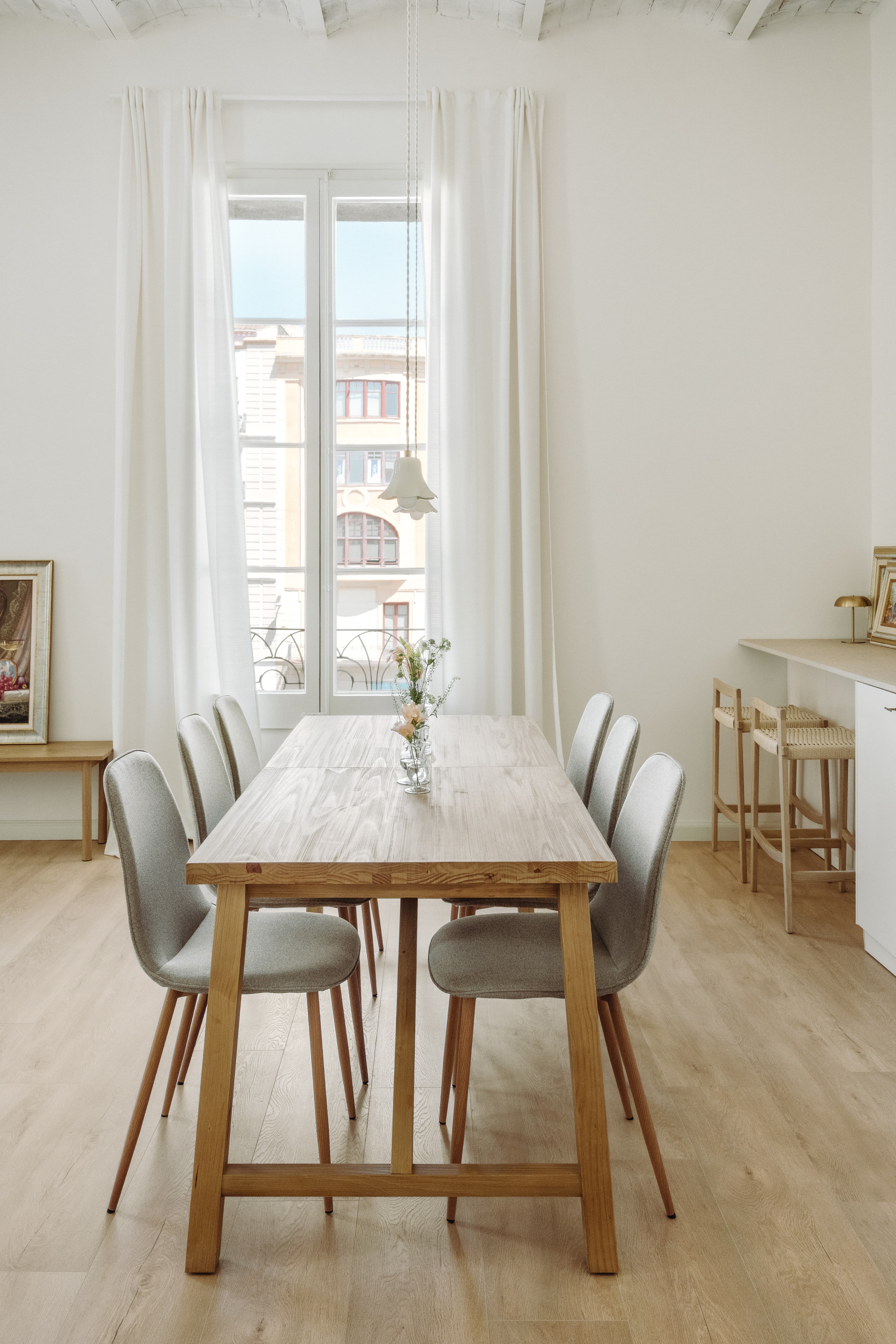 Mesa de comedor con flores, con puerta del balcon al fondo