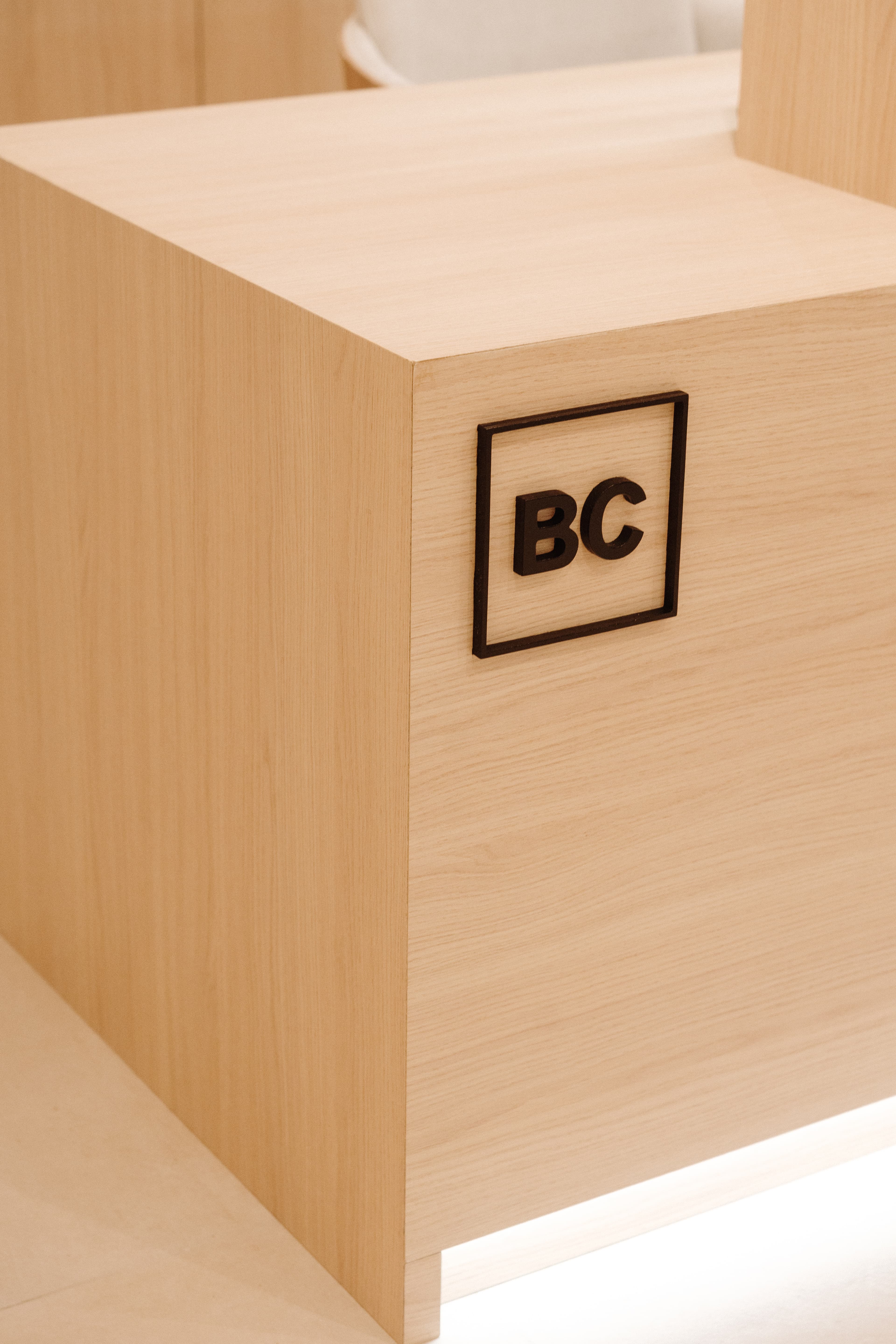 Detalle del lateral del mostrador, con el logo de la clínica en negro y relieve en la madera