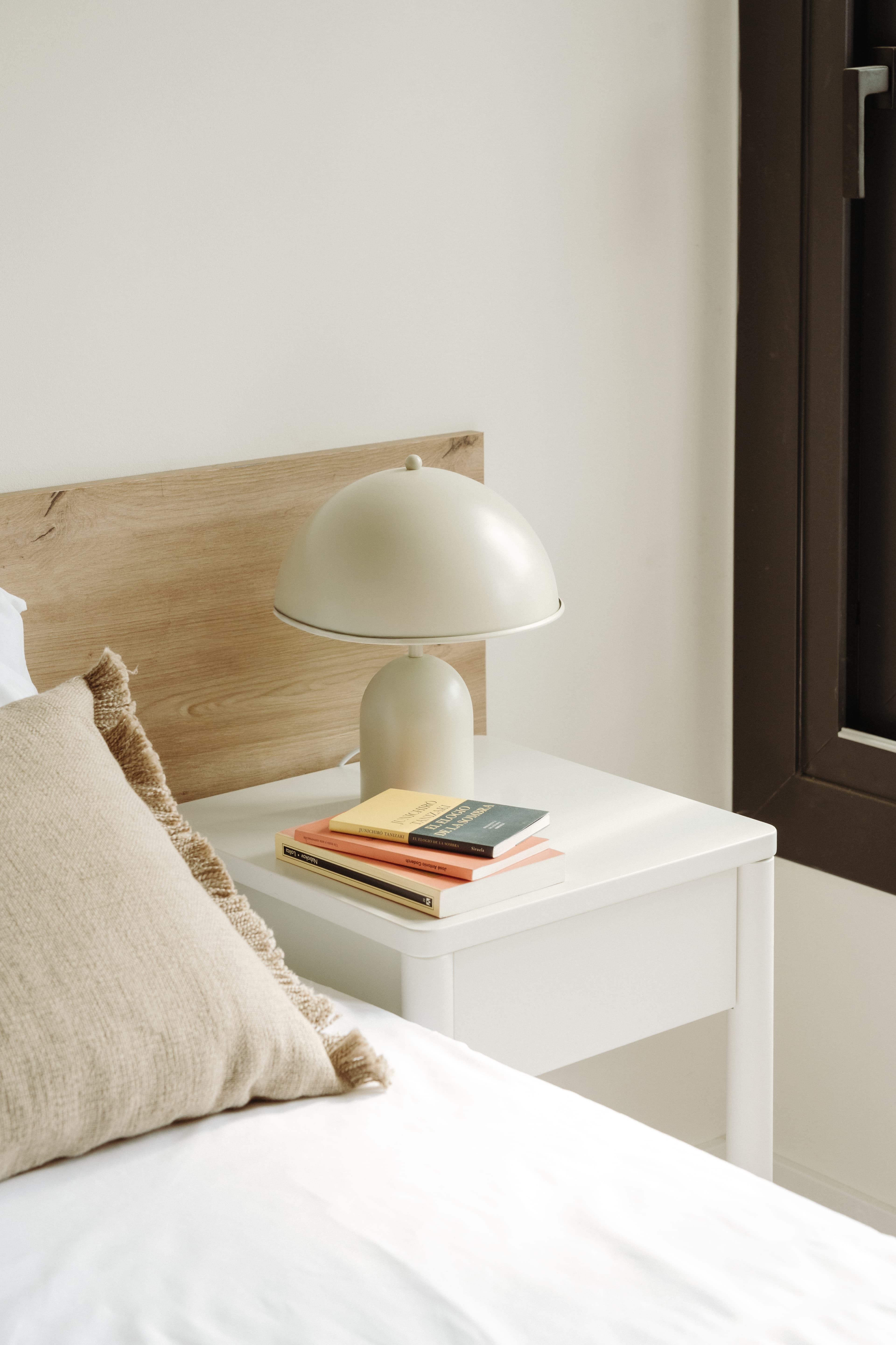 Detalle de la mesita de noche con lámpara y libros